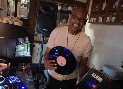 An image of a DJ in his studio holding a vinyl.