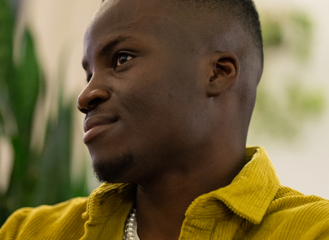A close up photo of poet Adjei Sun, wearing a bright yellow jacket.
