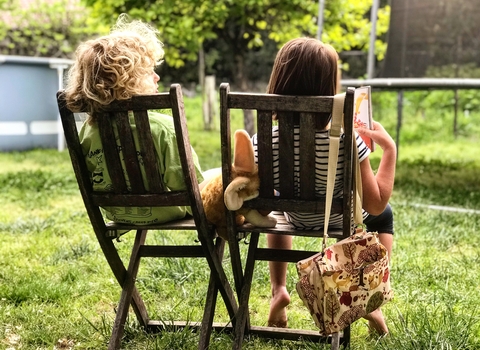 Two children sitting down in a garden